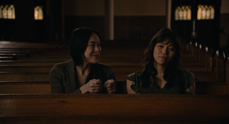 Trixie (left) and Olivia (right) sitting in some church pews reminiscing about the past and smiling.